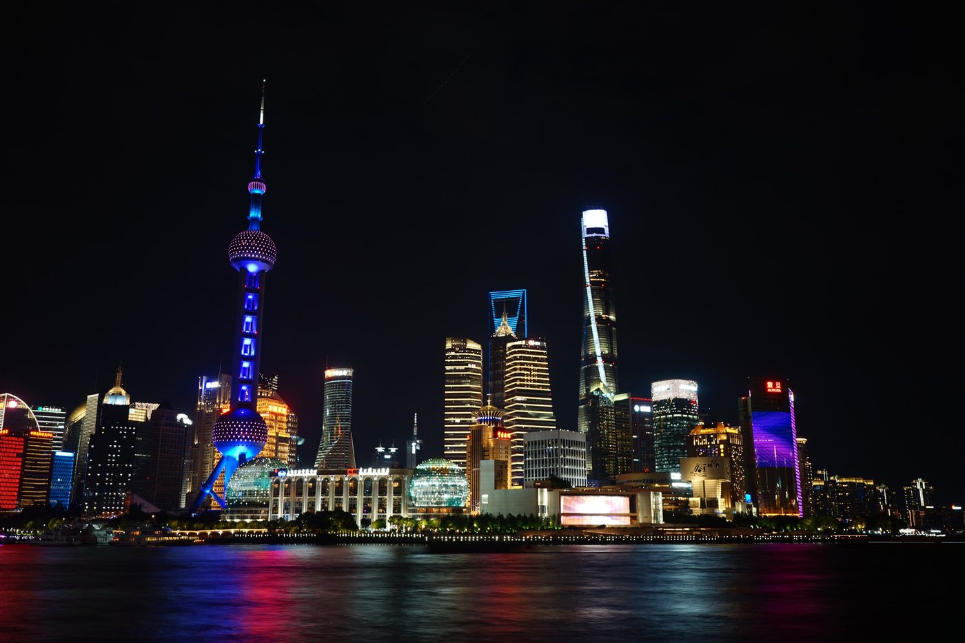 The Pudong skyline lit up at night across the river